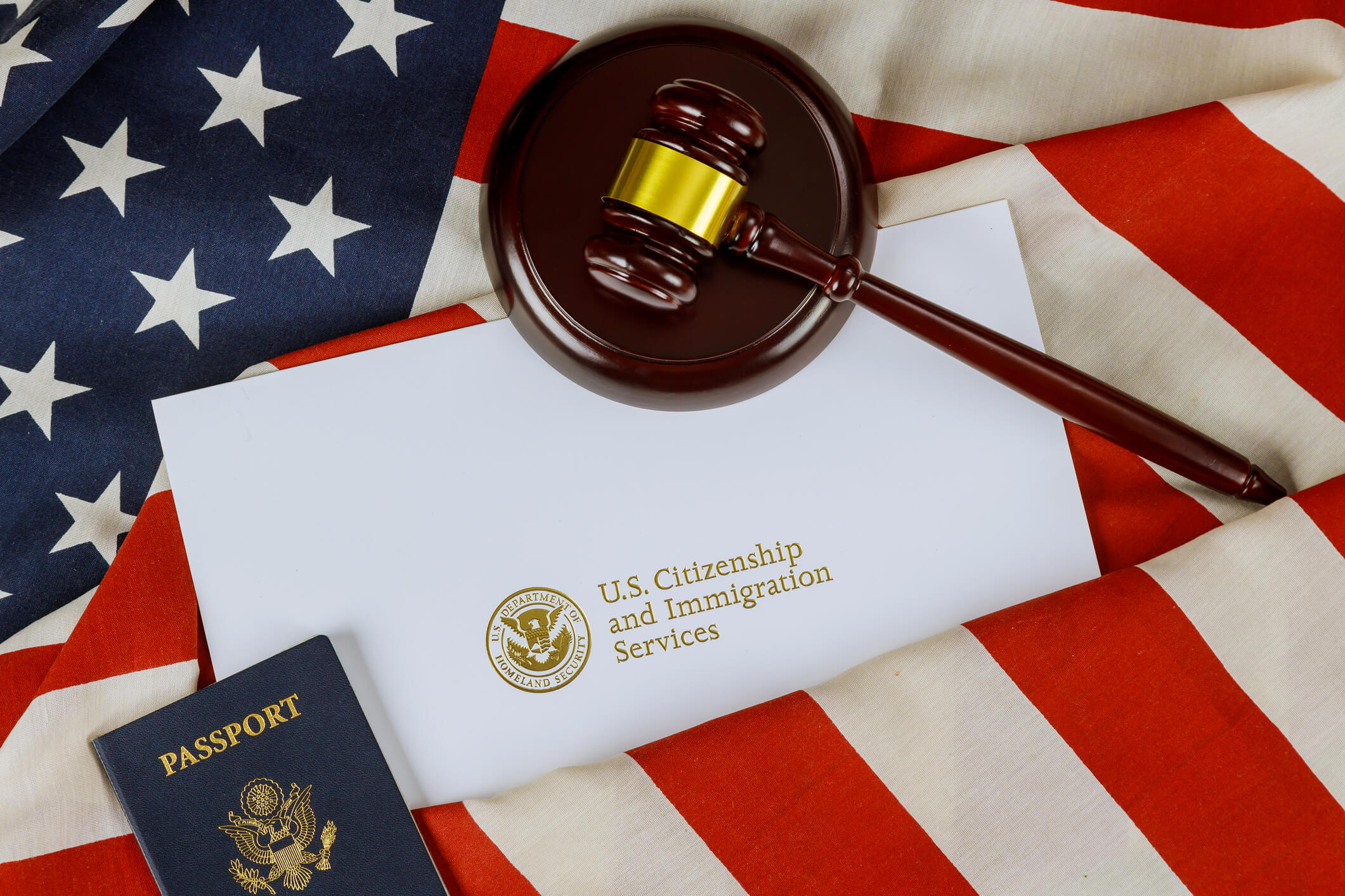a united states flag with a wooden gavel and document that says u.s immigration services representing the need for an immigration lawyer