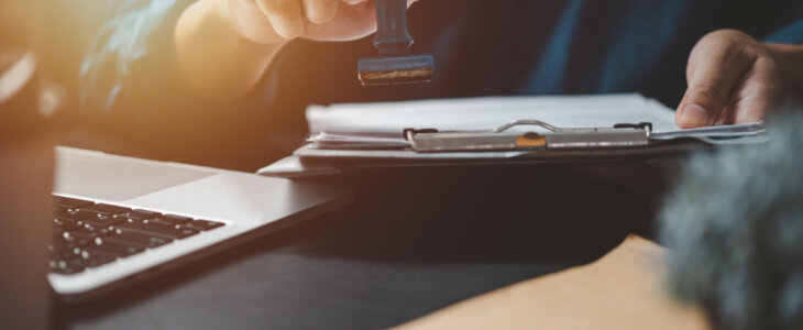 Man stamping approval of work finance banking or investment marketing documents on desk.