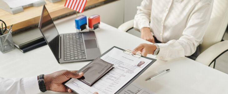 Young specialist taking document from man to make visa in visa center