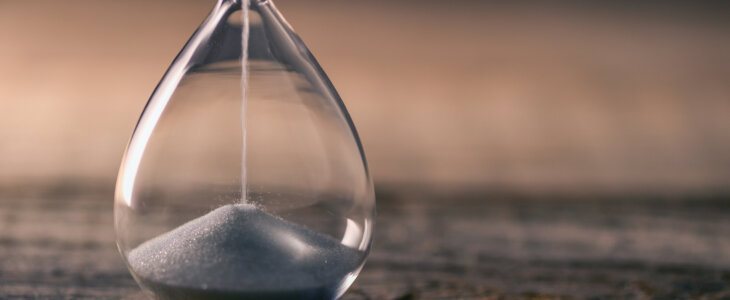 Flowing white hourglass on wooden table; Twilight blue